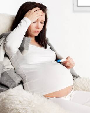 Pregnant woman with a thermometer at home. Pregnant woman illness, cold